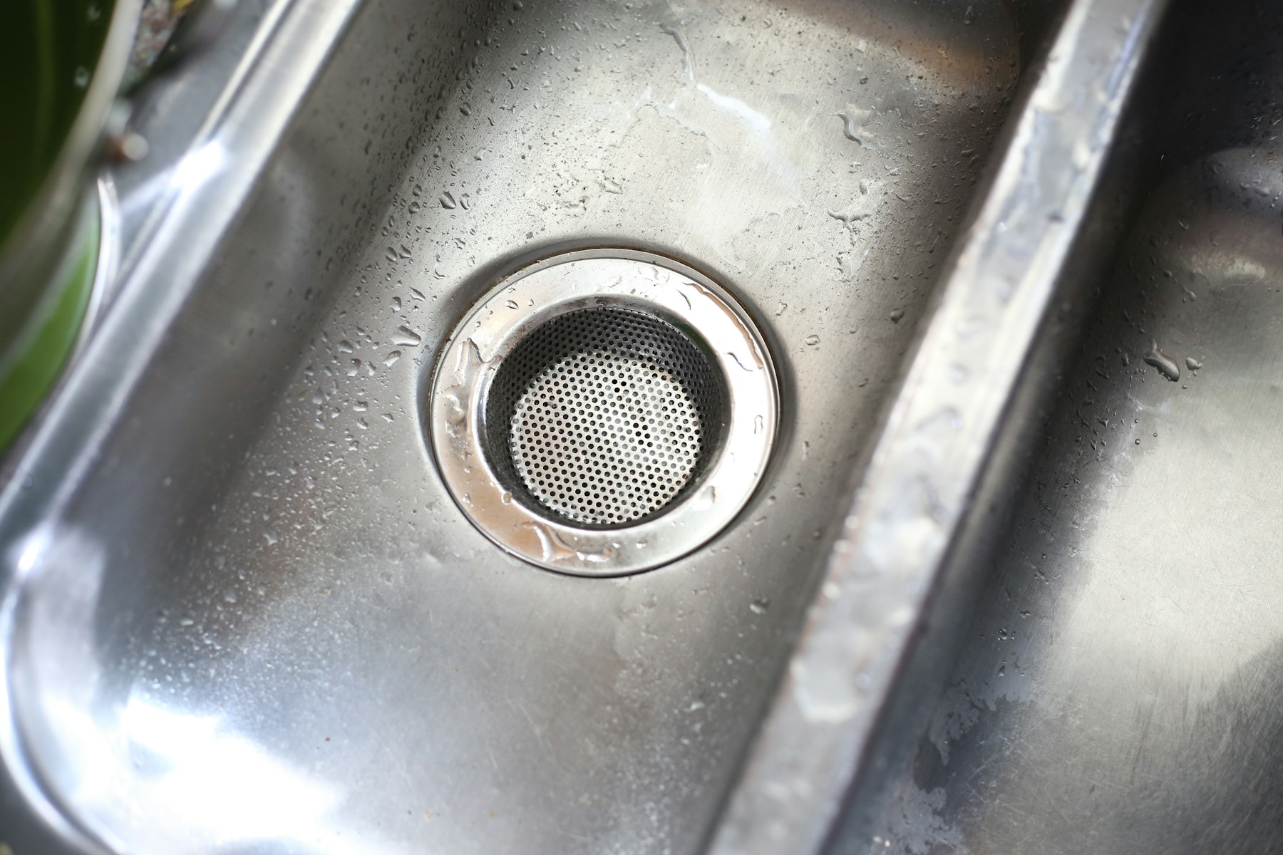 Close view of a stainless steel kitchen sink drain fitted with a removable strainer basket